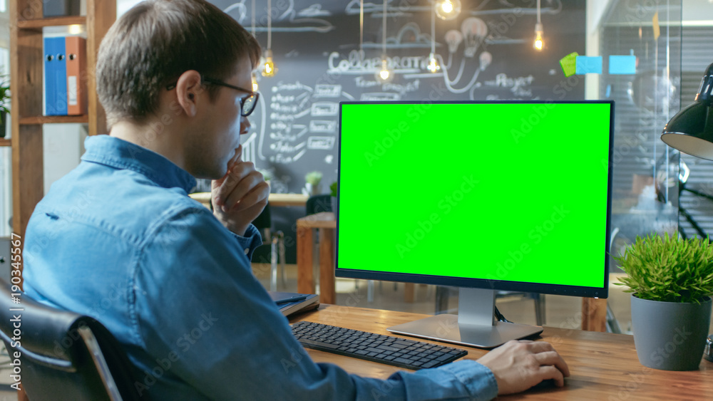 年轻人在办公桌上用模拟绿屏的个人电脑工作。背景嗨