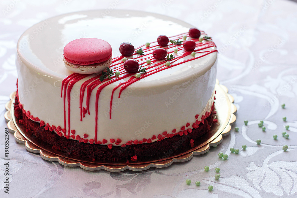 用红色浆果和马卡龙装饰的美味白色自制蛋糕