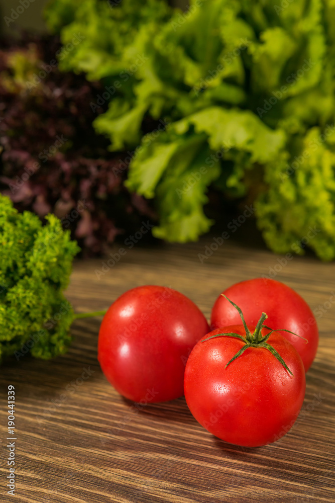 木桌上多汁的成熟西红柿，背景是新鲜的香草。新鲜的蔬菜。