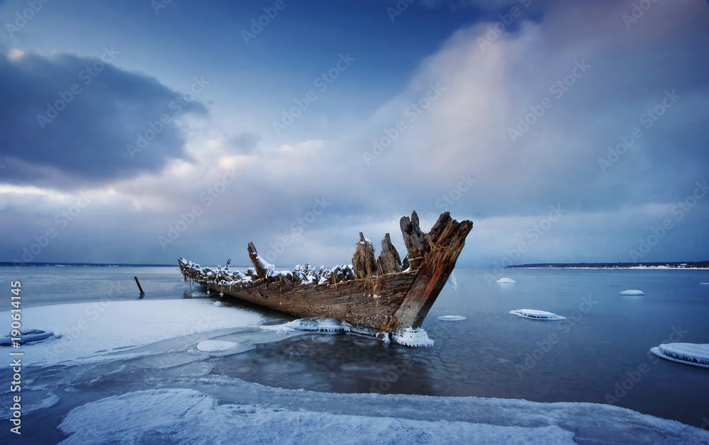 海上结冰的旧木制沉船。夜晚的水上冬天