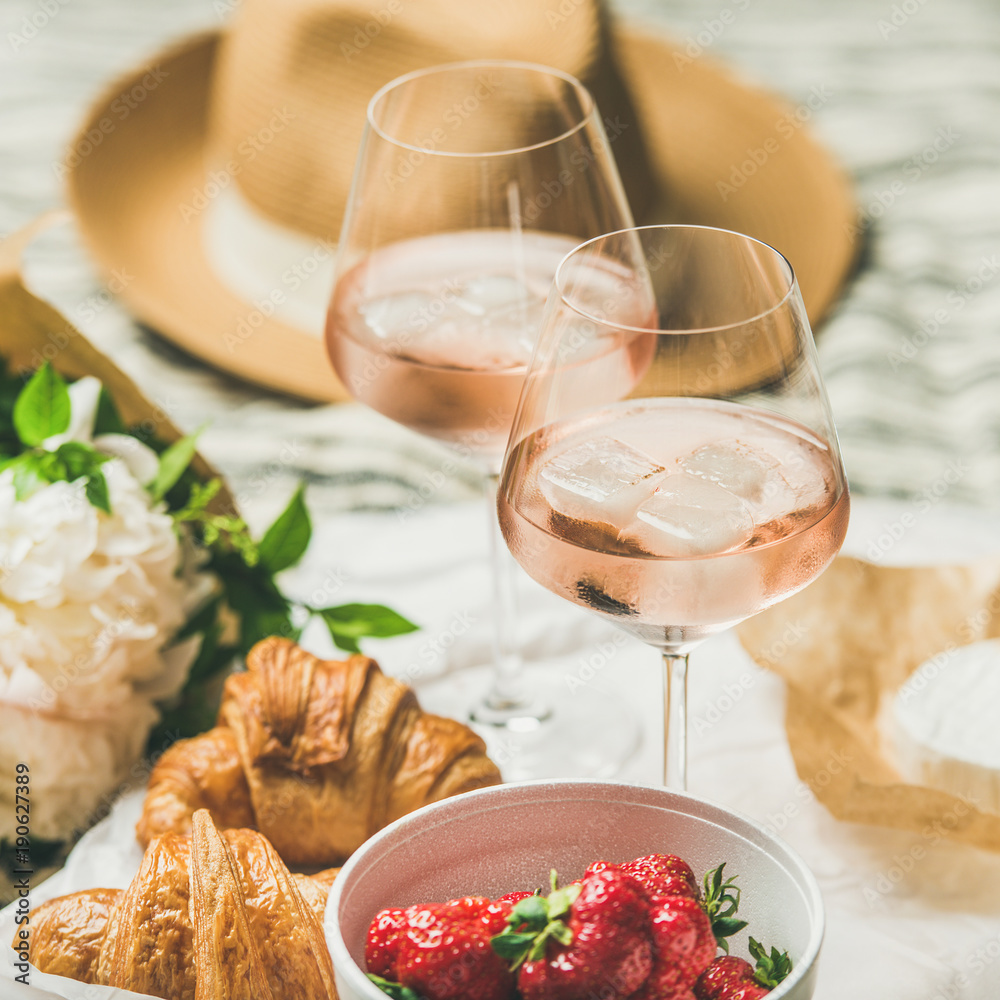 French style romantic summer picnic setting. Flat-lay of glasses of rose wine with ice, fresh strawb