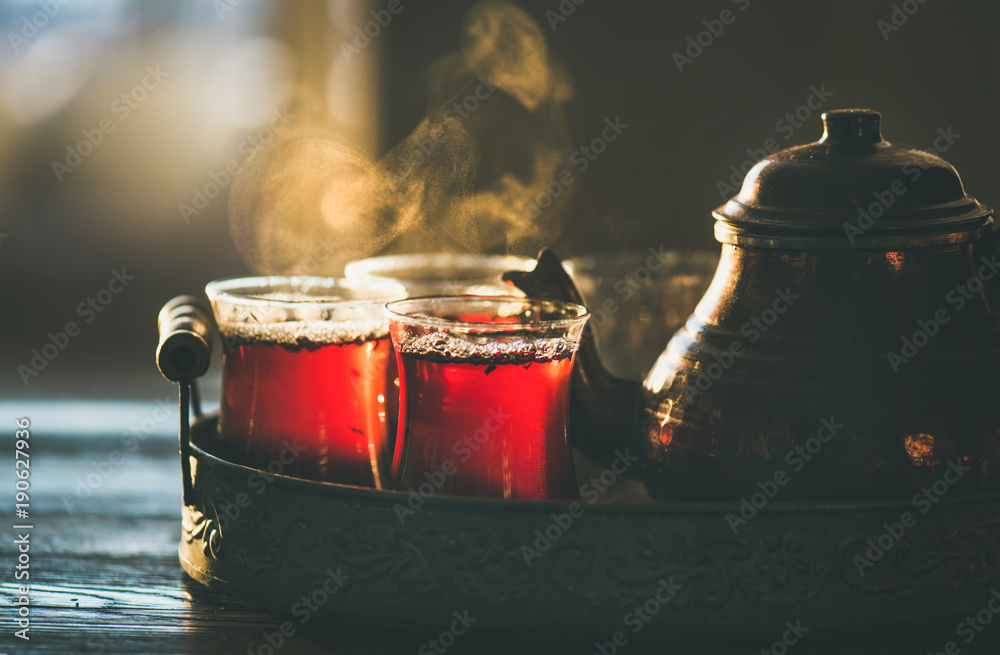 传统热气腾腾的土耳其茶，装在郁金香玻璃杯里，铜壶放在复古托盘里