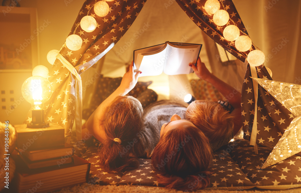 幸福的家庭母亲和孩子在家里的帐篷里看书