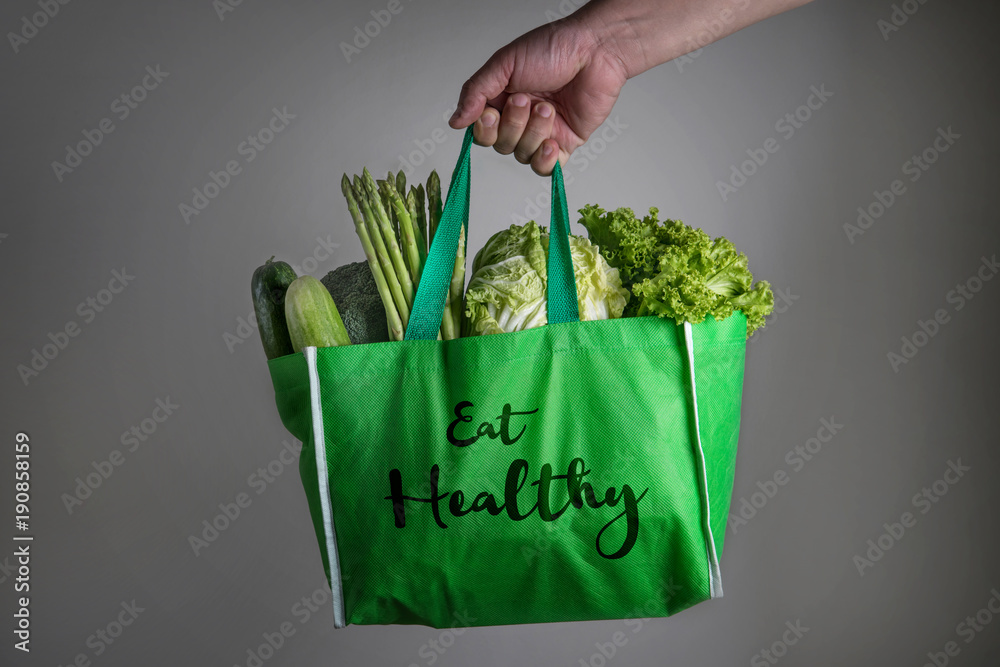 合上一个手拿的绿色食品袋，上面写着混合有机绿色蔬菜的Eat Healthy文本，