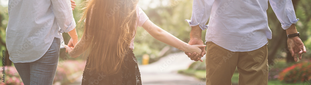 幸福的家庭母亲父亲和女儿在日落时手牵着手在大自然上行走
