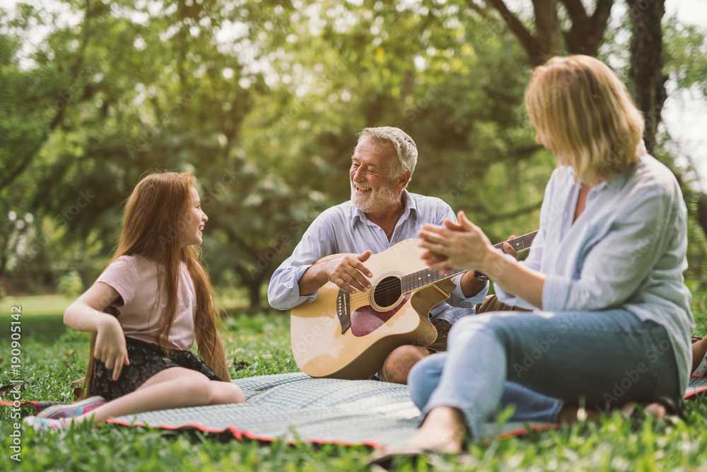 一家人享受美好时光，在他们的绿色公园花园里弹吉他。