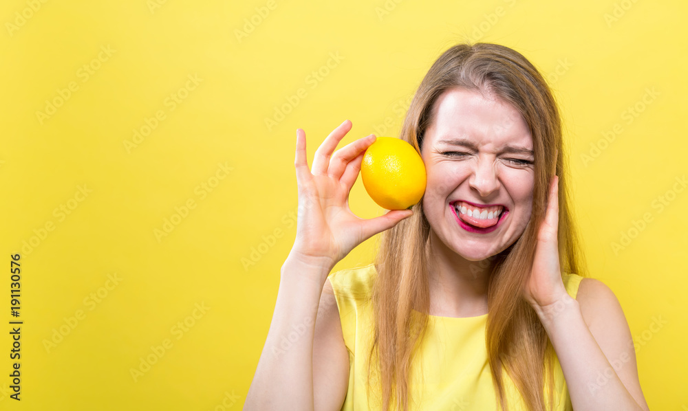 快乐的年轻女人拿着黄色背景的柠檬
