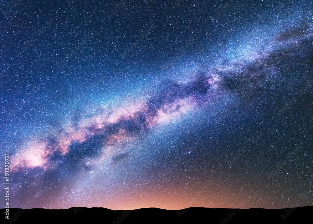 银河系。奇妙的夜晚景观，紫色的银河系，天空布满星星，黄色的灯光和山丘