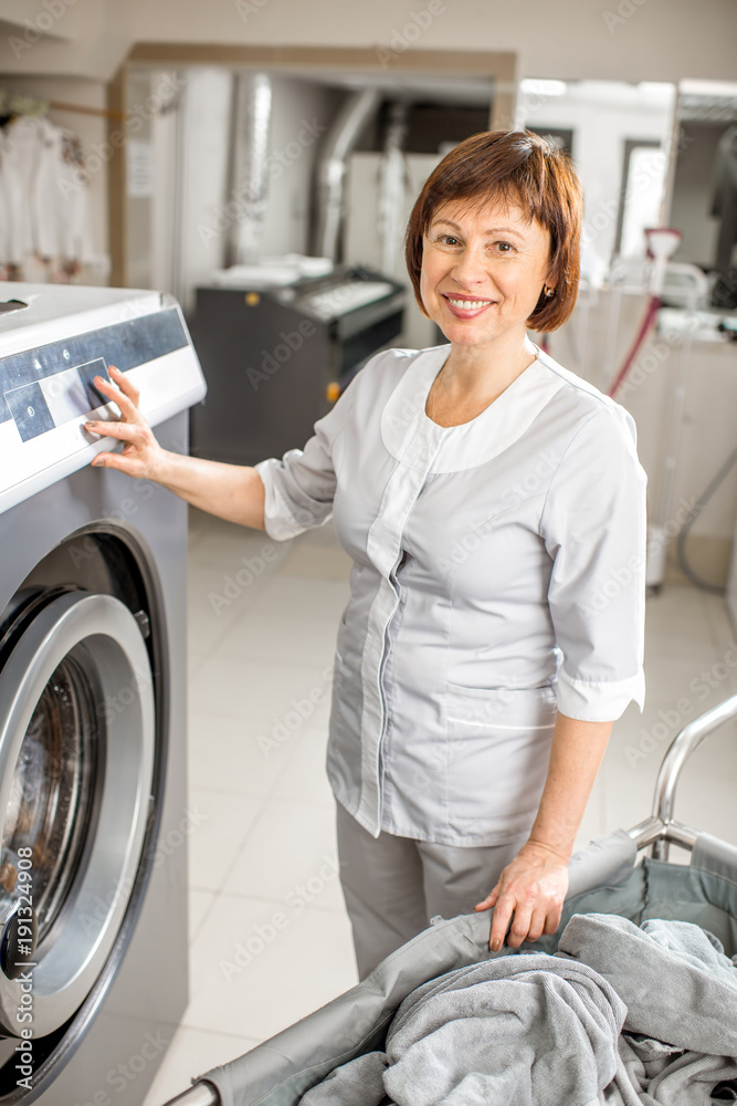 一位资深洗衣女工拿着洗衣篮站在专业酒店洗衣房的肖像