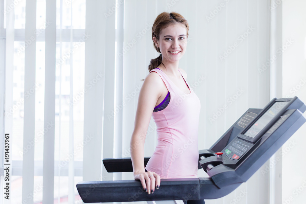 高加索女性带着微笑和幸福在跑步机上锻炼