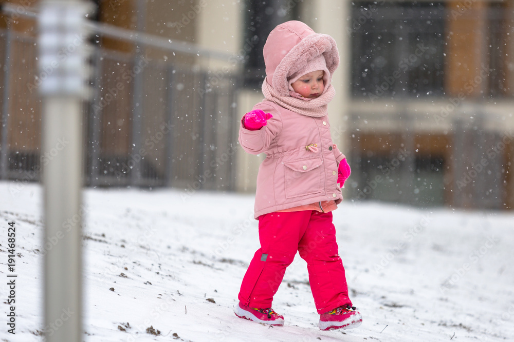 穿着冬季夹克在雪地上奔跑的可爱女孩