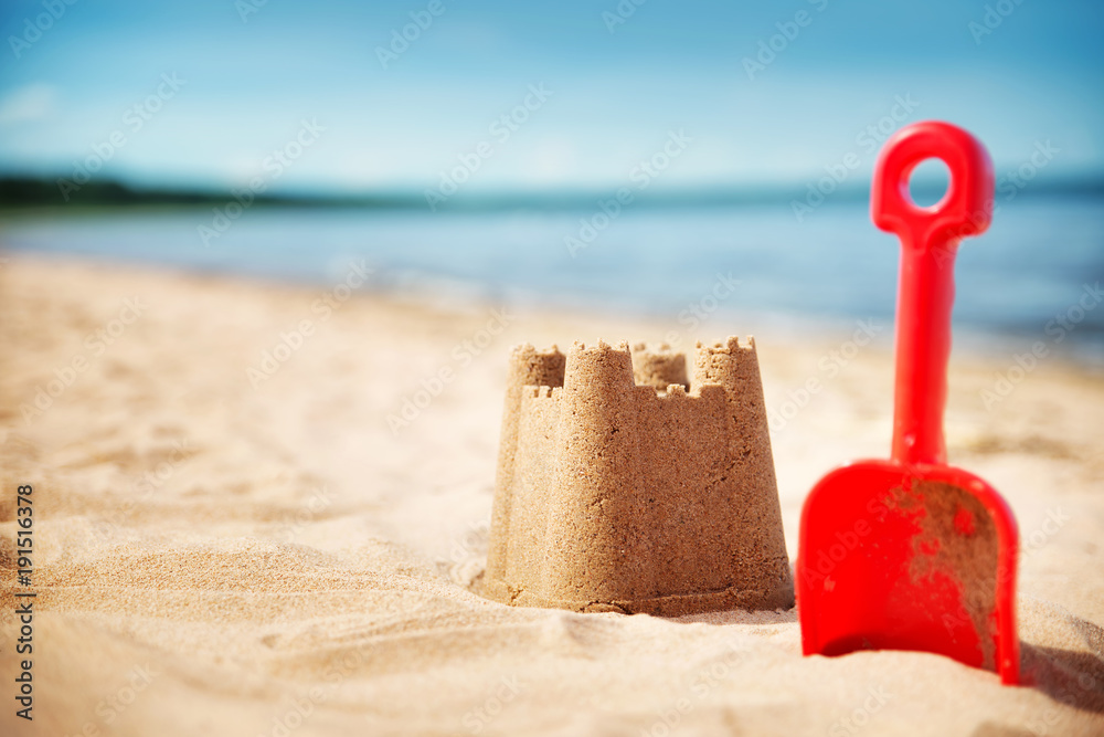 夏天在海上用铲子建造沙堡。美丽的日子在海边。海滩上的沙子和