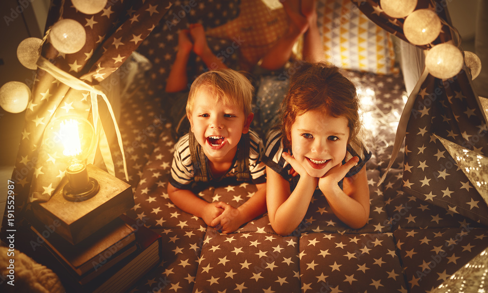 快乐家庭的孩子，兄弟姐妹在游戏室的黑暗帐篷里玩耍、大笑和拥抱