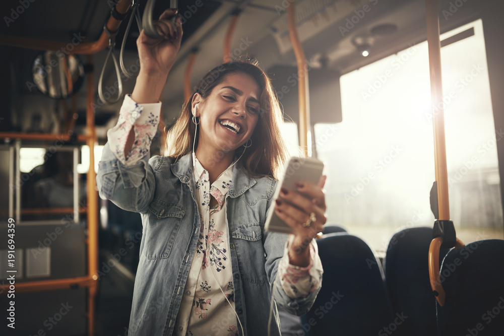 年轻女子在公交车上听音乐时大笑