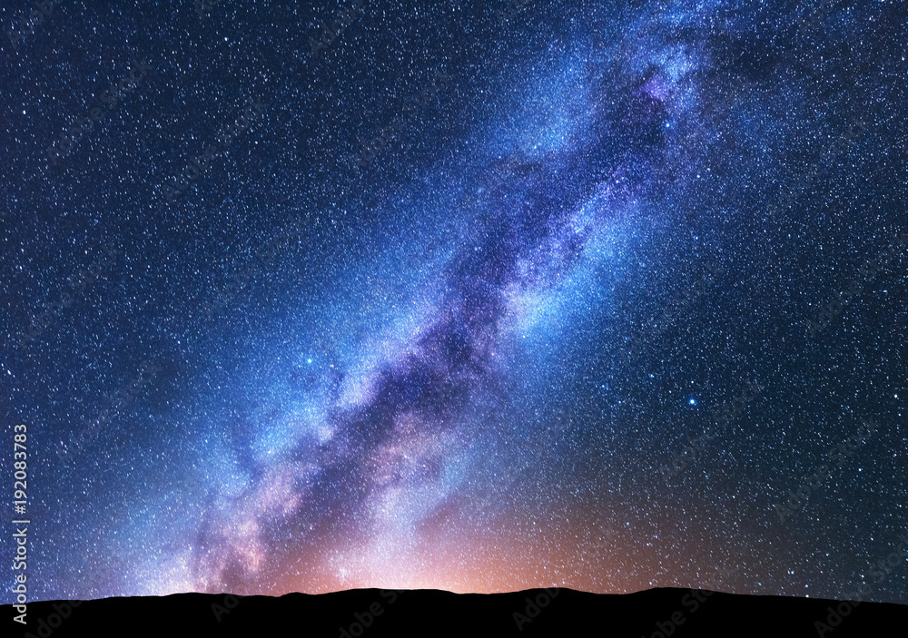 银河系。明亮的银河系、布满星星的天空、黄色的灯光和山丘的奇妙夜景
