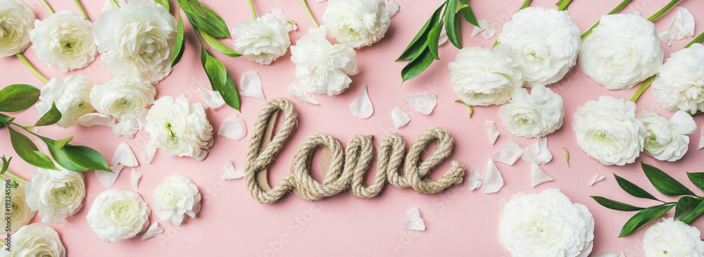 圣瓦伦丁节背景。白色毛茛花的平面布置，浅粉色上有爱的字样
