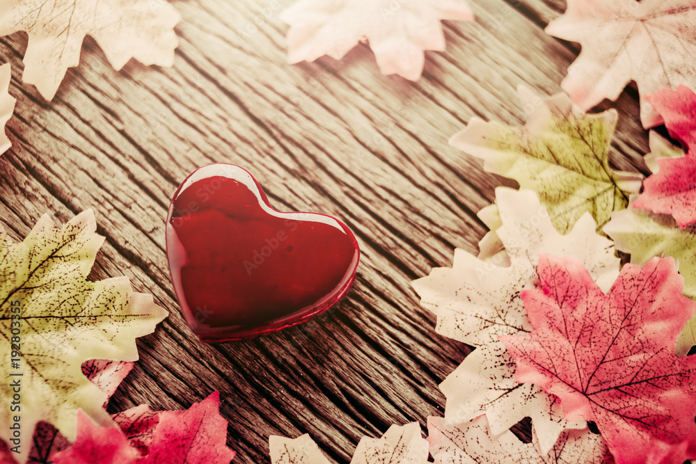 情人节爱情创意概念，木桌上有橙色叶子和红色心形物体