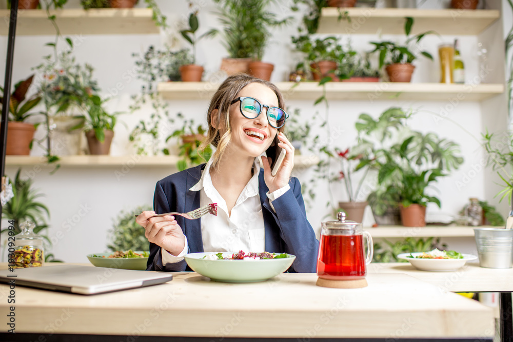 一位女商人在午餐时吃沙拉，坐在美丽的g上的素食餐厅