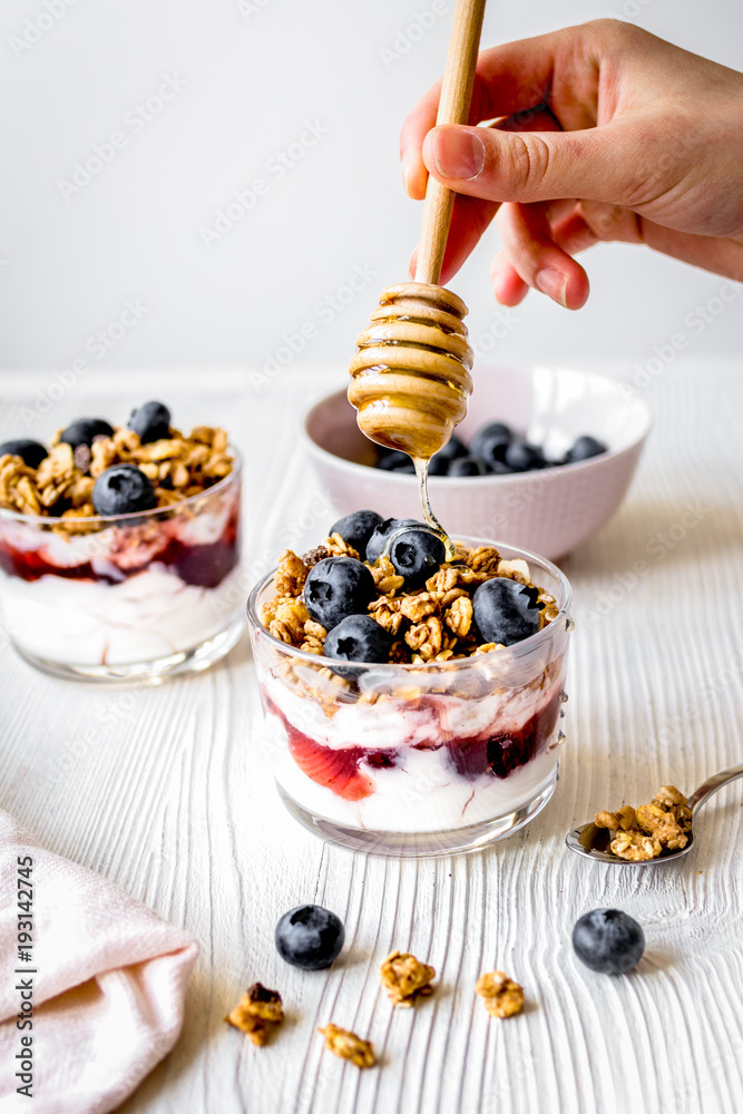 Cooking breakfast with granola and berries on white kitchen back