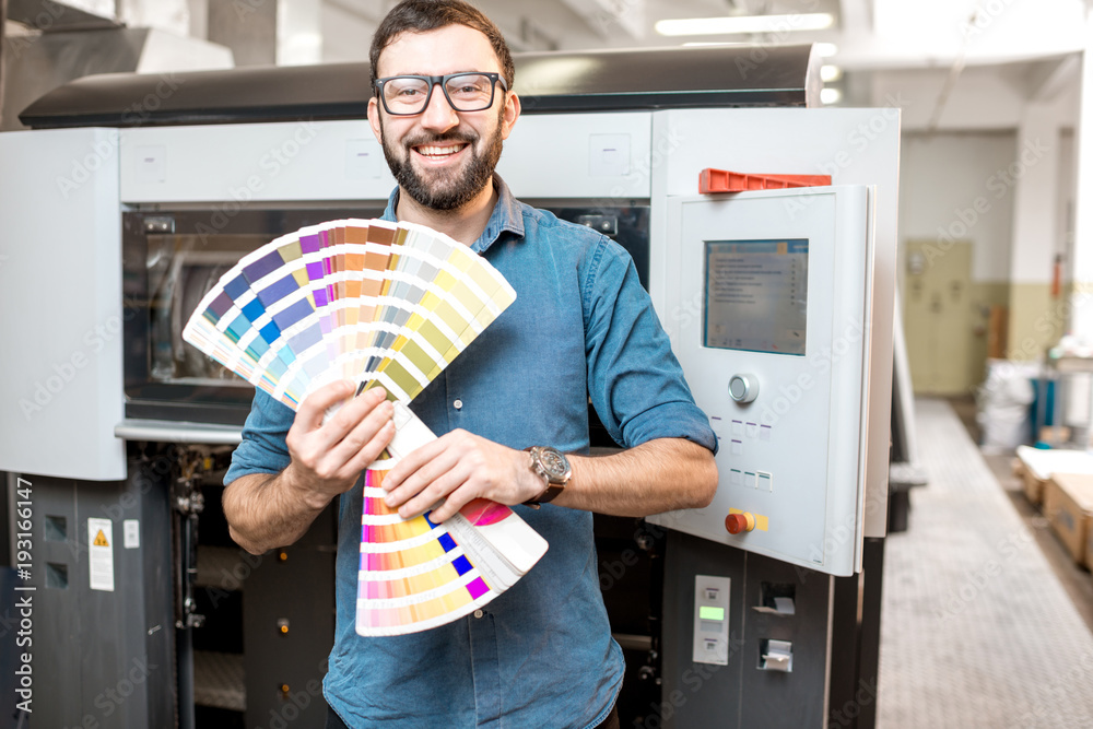 印刷师拿着色板站在印刷制造厂的有趣画像