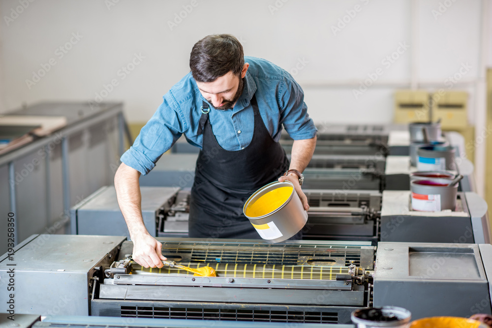 印刷制造厂的打字机向胶印机填充黄色油漆