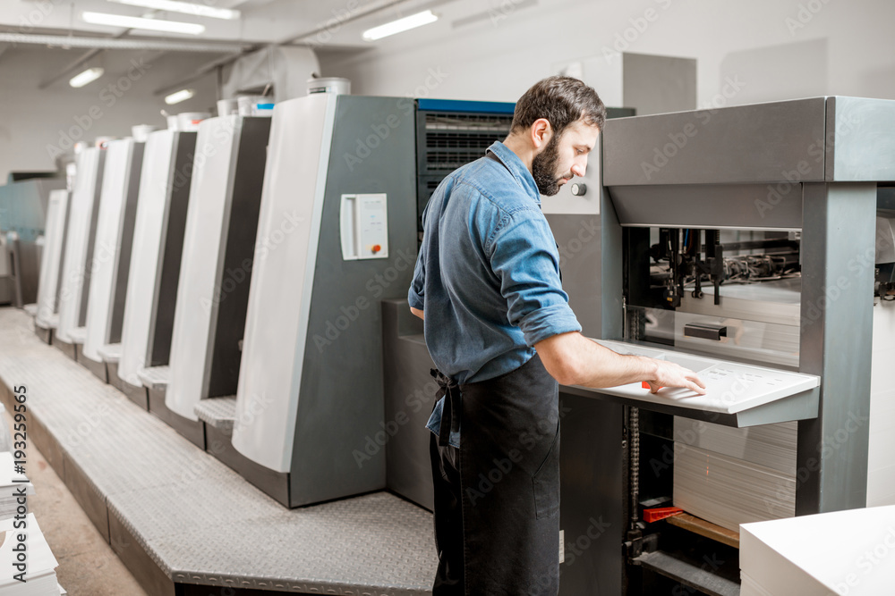 印刷操作员在印刷制造厂使用胶印机工作