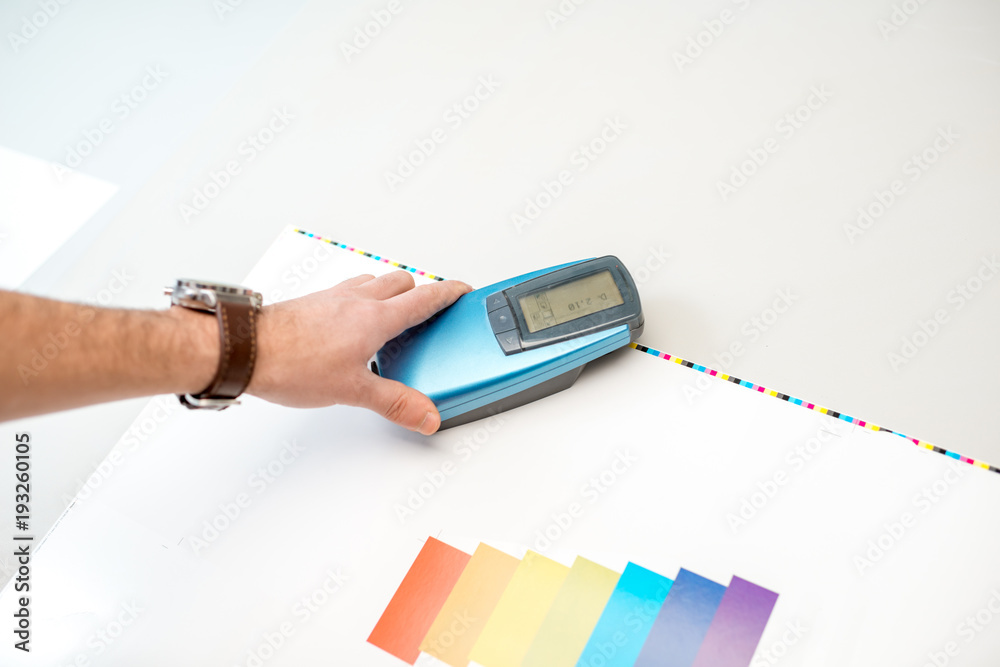 在打印计划的操作台上使用光谱仪工具测量纸质打印上的颜色