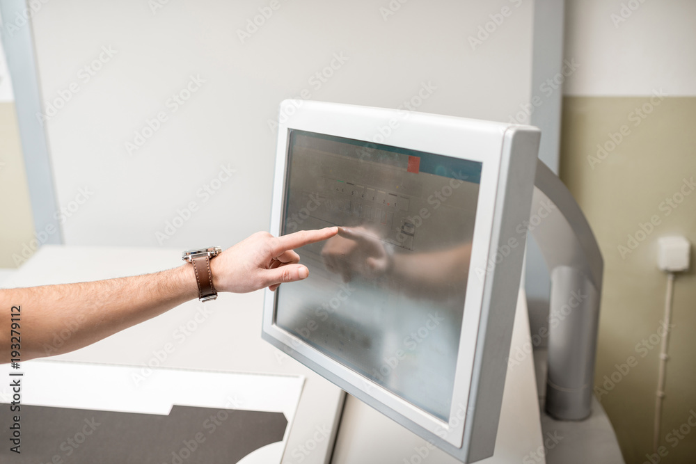 男子在印刷厂的操作台上触摸屏幕设置印刷机