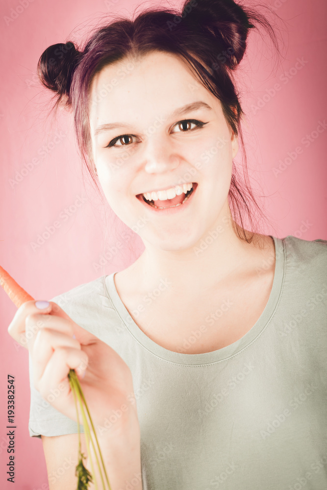 微笑的年轻少女拿着富含维生素的胡萝卜看着镜头