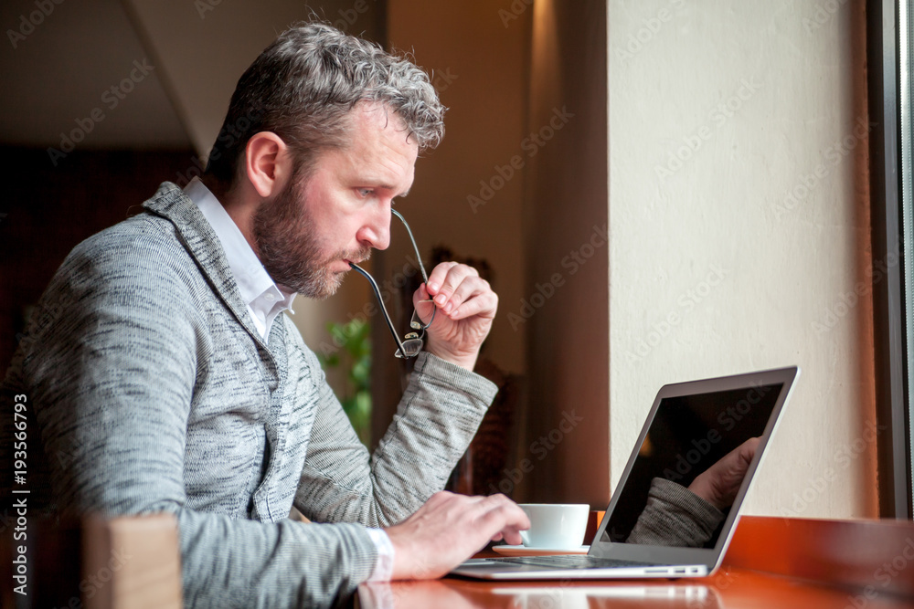 一名男子在咖啡馆用笔记本电脑工作