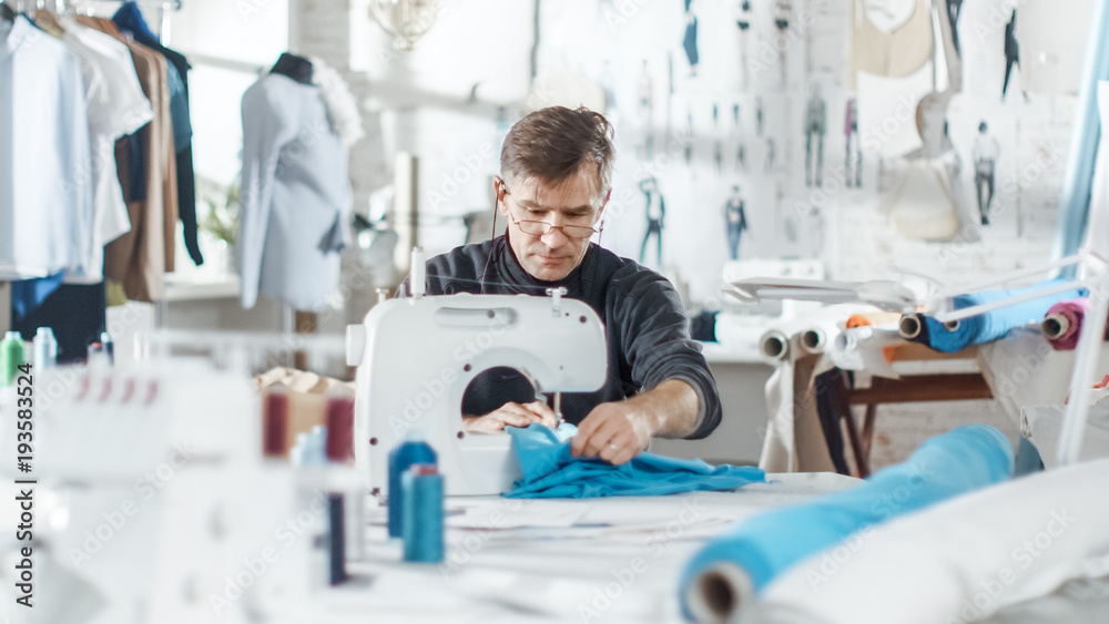 男时装、设计师/服装师在阳光工作室的缝纫机上工作。各种缝纫