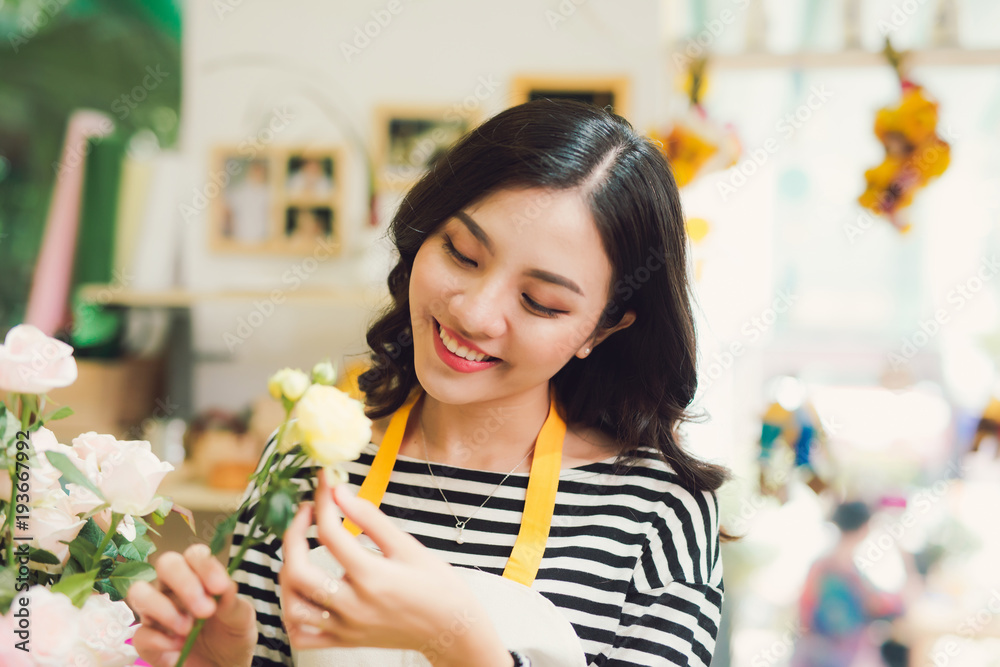 年轻漂亮的亚洲女孩花商在工作场所打理鲜花。