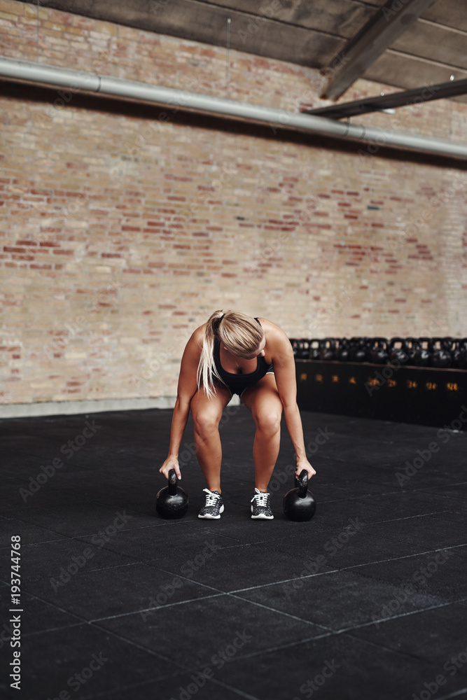 专注的年轻女性在健身房锻炼举重