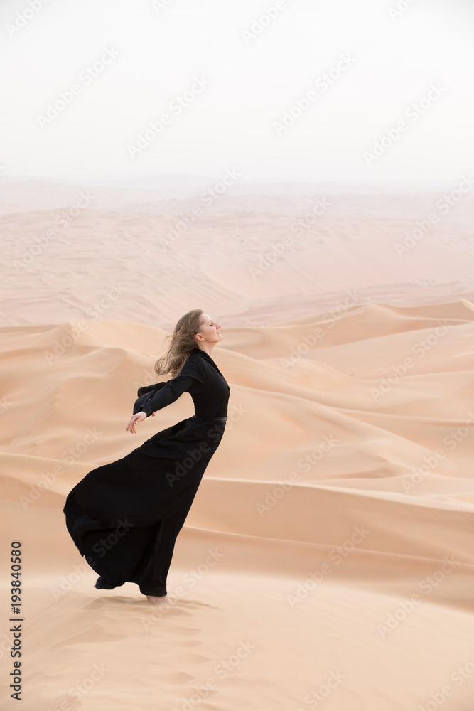年轻漂亮的高加索女子穿着传统的阿联酋连衣裙摆姿势——空区的阿巴亚
