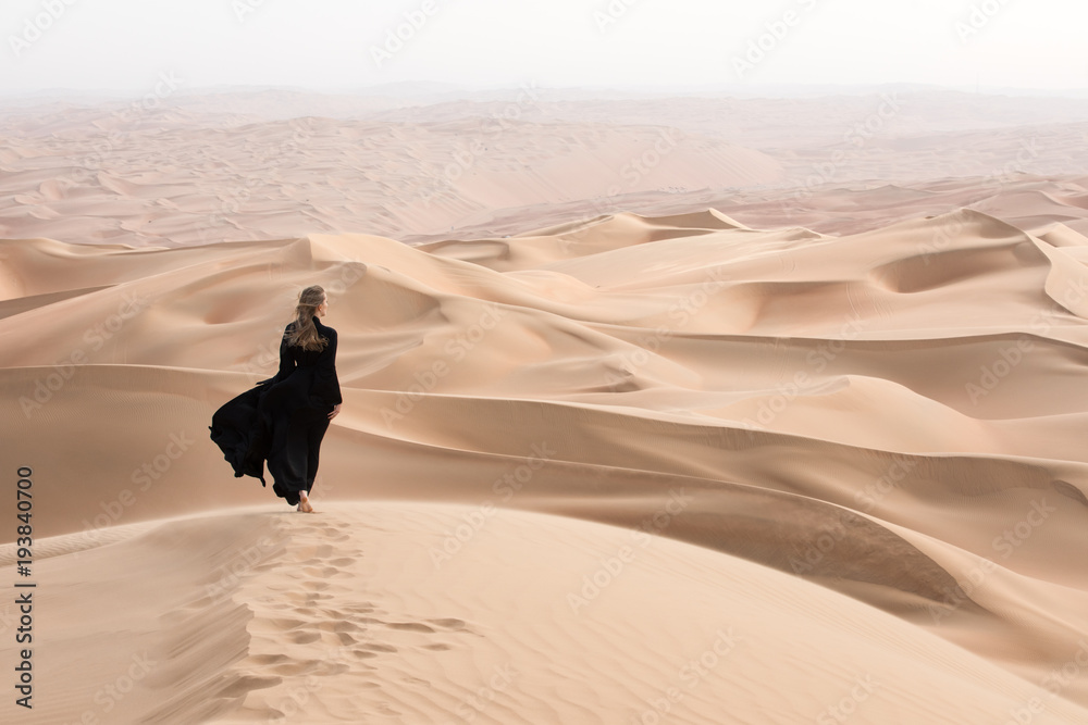 Young beautiful Caucasian woman posing in a traditional Emirati dress - abaya in Empty Quarter deser