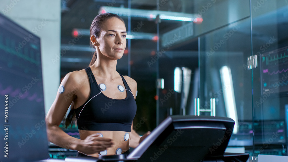 体育科学中戴着电极在跑步机上跑步的美女运动员