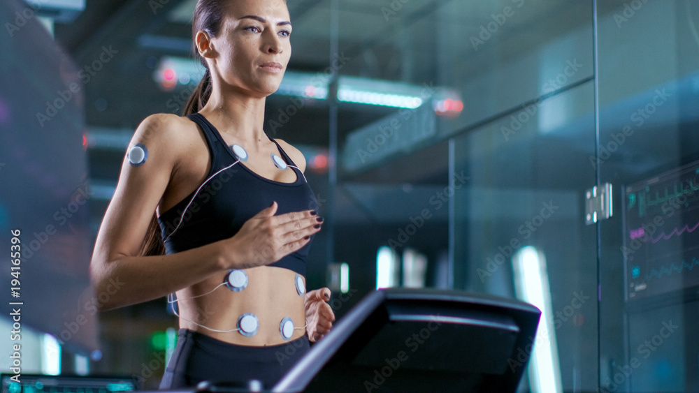 美女运动员在跑步机上跑步，身上绑着电极。在后台分娩