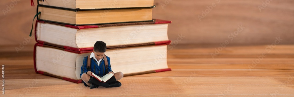 男孩在一堆书旁边的地板上看书