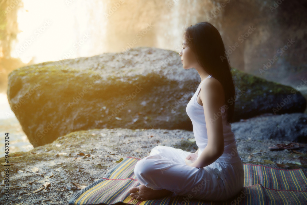 一个女人在瀑布边做瑜伽和冥想
