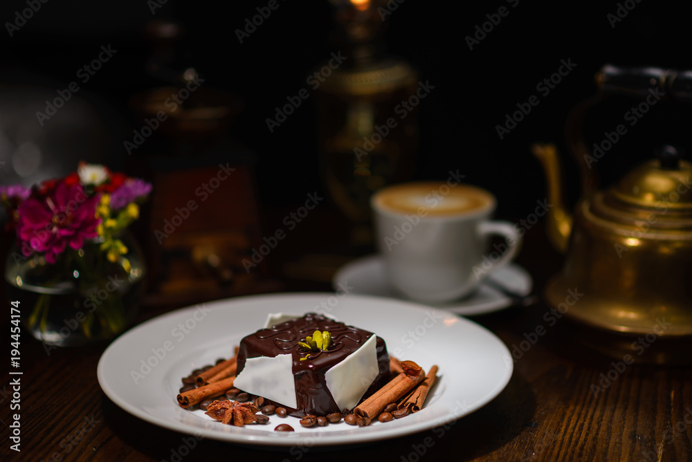 高级美食，巧克力甜点配肉桂棒，背景是一杯咖啡和咖啡m