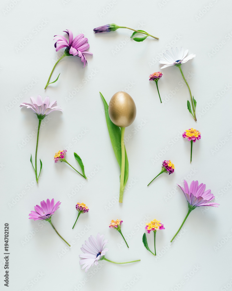 复活节彩蛋布局由五颜六色的花朵、绿色的叶子和金色的彩蛋组成。最小的复活节概念。佛罗里达州