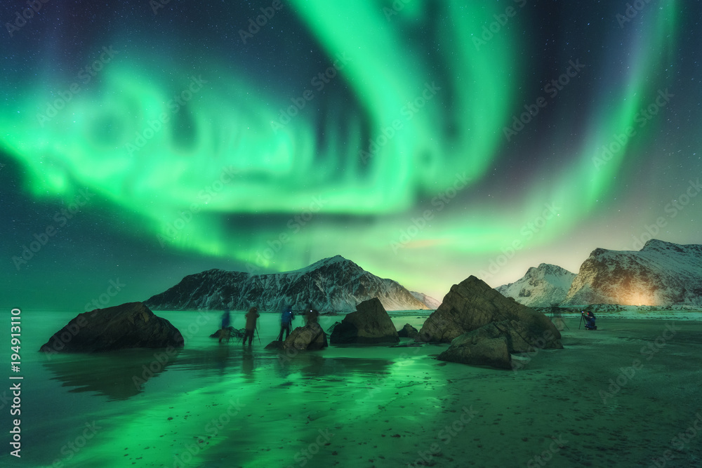 绿色北极光和摄影师。极光。挪威罗弗敦群岛的北极光。星空