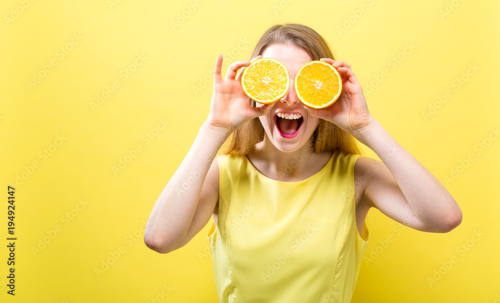 快乐的年轻女人在坚实的背景上拿着橘子