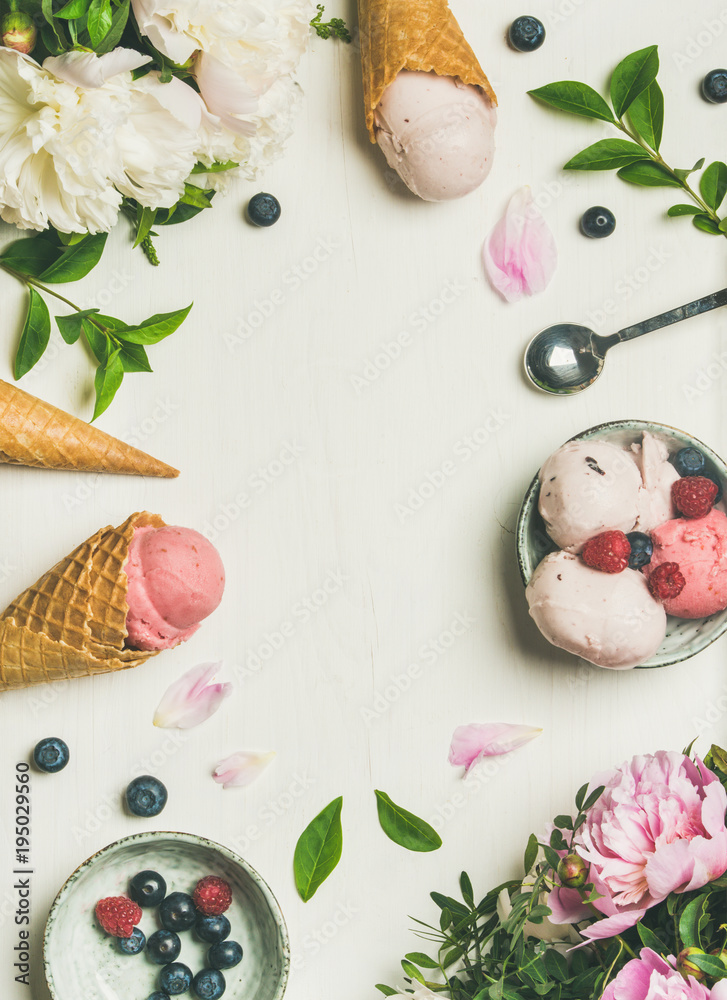 Flat-lay of pink strawberry and coconut ice cream scoops, sweet cones and peony flowers bouquet over