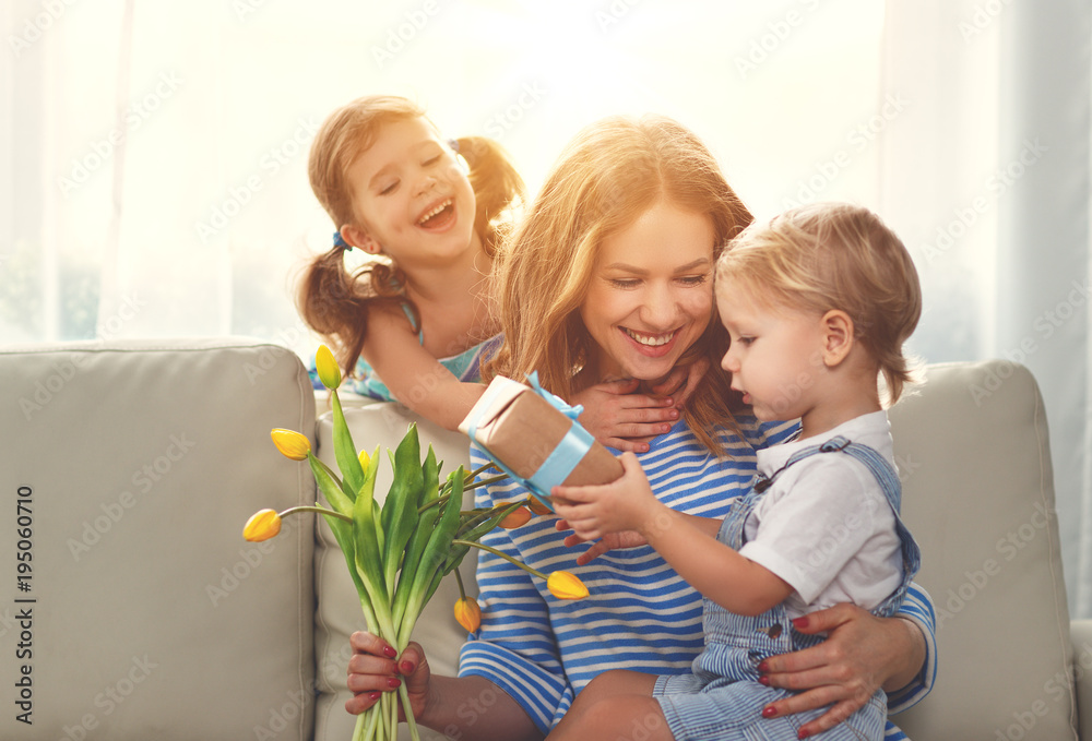 Happy mothers day! Children congratulates moms and gives her a gift and flowers