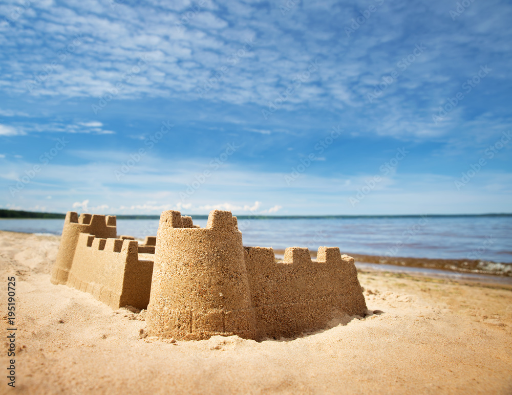夏天海边的沙堡。美丽的海滨。海滩上的沙子和蓝色的海水