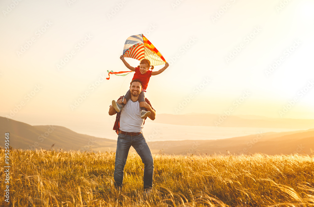 幸福的家庭父亲和孩子女儿在草地上放风筝跑步。