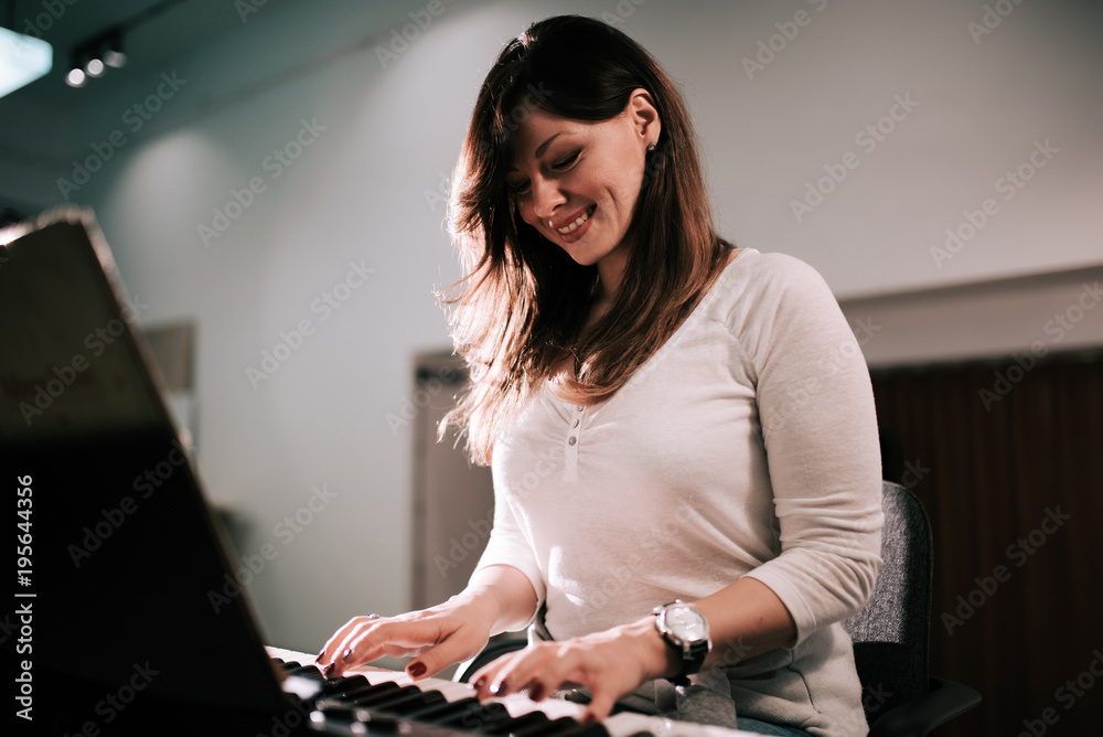弹奏合成器钢琴的迷人年轻女子。