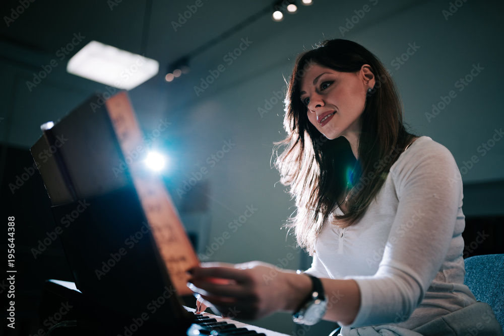 一位女钢琴家在演奏时翻动乐谱的画面。