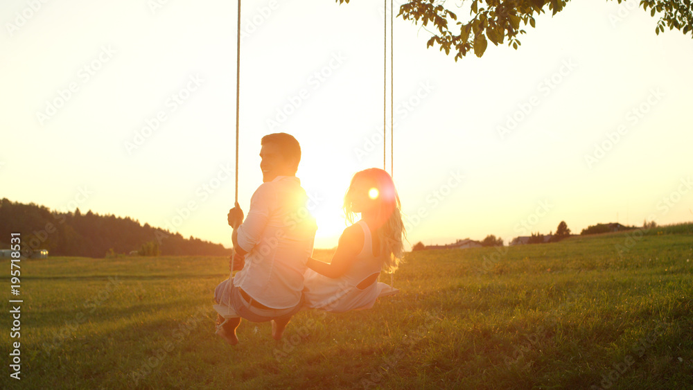 镜头闪耀：幸福的年轻情侣在金色的日落下对着镜头摇摆微笑